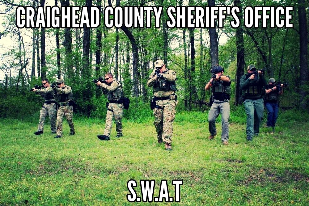Swat Team Member walking through field with guns drawn